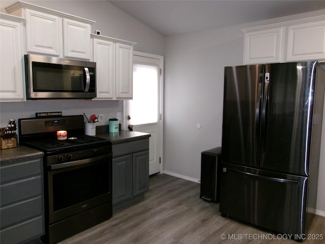 7882 E 132nd Pl S, Bixby, OK 74008 - kitchen featuring appliances with stainless steel finishes, wood finished floors, dark countertops, white cabinetry, and lofted ceiling
