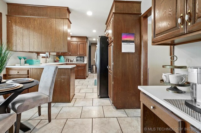 7329 E 66th Ct, Tulsa, OK 74133 - kitchen featuring freestanding refrigerator, light countertops, recessed lighting, light tile patterned floors, and a peninsula