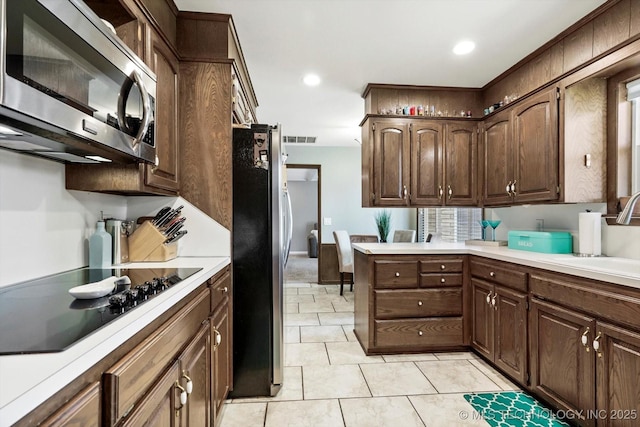 7329 E 66th Ct, Tulsa, OK 74133 - kitchen with appliances with stainless steel finishes, a sink, light countertops, light tile patterned flooring, and dark brown cabinets