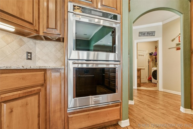 18578 S 269th E Ave, Haskell, OK 74436 - kitchen featuring stainless steel double oven, washer / dryer, ornamental molding, tasteful backsplash, and light wood-style flooring