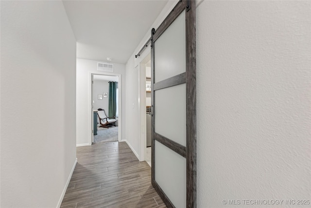 7000 S Elder Ave, Broken Arrow, OK 74011 - hallway featuring a barn door, dark wood finished floors, and baseboards
