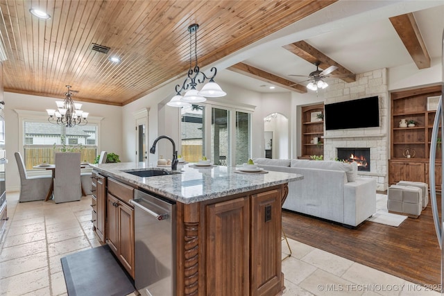 5314 E 125th St S, Bixby, OK 74008 - kitchen with stainless steel dishwasher, a sink, a fireplace, stone tile flooring, and brown cabinetry