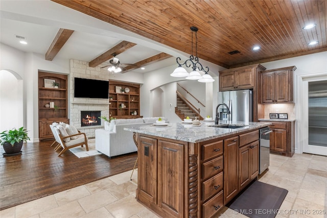 5314 E 125th St S, Bixby, OK 74008 - kitchen featuring arched walkways, stainless steel appliances, a sink, a stone fireplace, and beamed ceiling