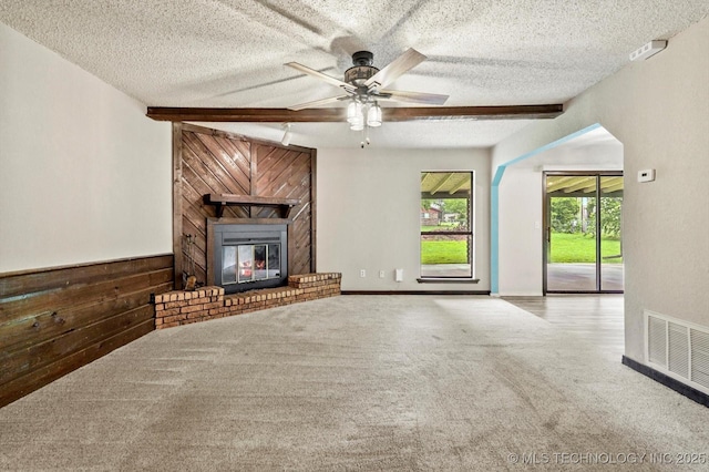 32112 E 721st Rd, Wagoner, OK 74467 - unfurnished living room with carpet floors, wood walls, a ceiling fan, a fireplace, and a textured ceiling