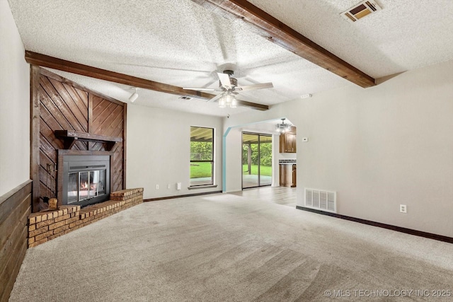 32112 E 721st Rd, Wagoner, OK 74467 - unfurnished living room with a textured ceiling, a fireplace, beamed ceiling, ceiling fan, and carpet flooring
