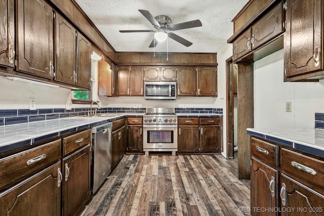 32112 E 721st Rd, Wagoner, OK 74467 - kitchen with appliances with stainless steel finishes, a sink, a textured ceiling, ceiling fan, and dark wood finished floors