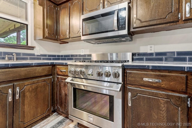 32112 E 721st Rd, Wagoner, OK 74467 - kitchen with stainless steel appliances, light wood-type flooring, dark brown cabinetry, and backsplash