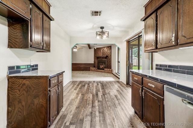 32112 E 721st Rd, Wagoner, OK 74467 - kitchen with dishwasher, a ceiling fan, dark wood finished floors, a fireplace, and dark brown cabinetry