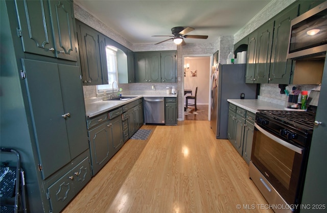 120 S Camden St, Muskogee, OK 74403 - kitchen with appliances with stainless steel finishes, light countertops, a sink, a ceiling fan, and light wood-type flooring