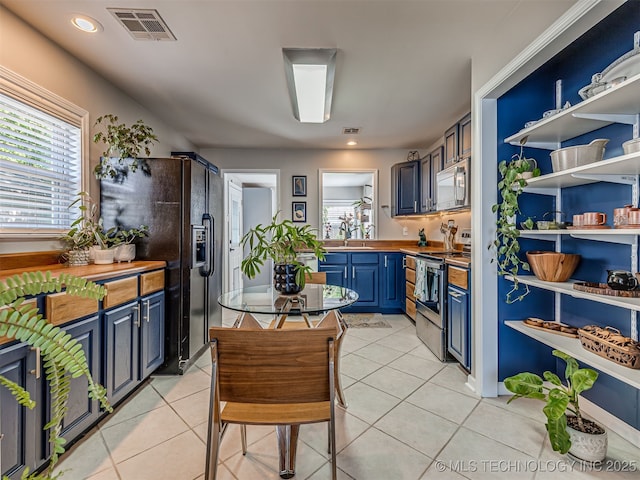 3215 W 41st St, Tulsa, OK 74107 - kitchen featuring stainless steel range with electric stovetop, blue cabinetry, white microwave, black fridge with ice dispenser, and open shelves