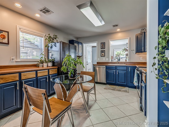 3215 W 41st St, Tulsa, OK 74107 - kitchen featuring stainless steel appliances, blue cabinetry, light tile patterned floors, a sink, and recessed lighting