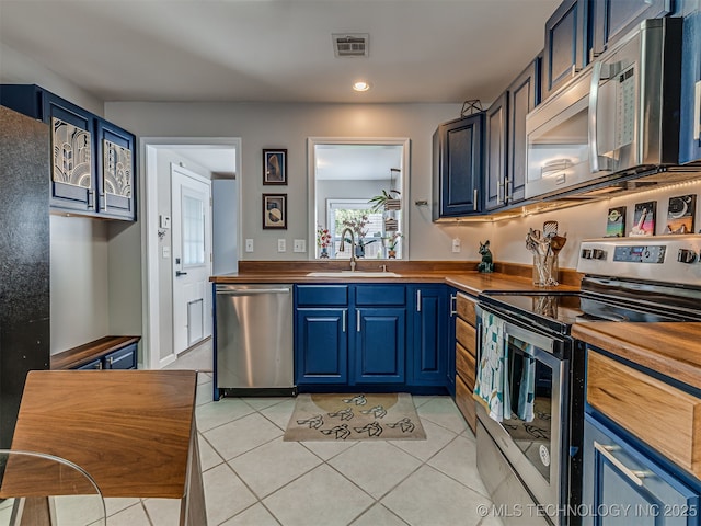 3215 W 41st St, Tulsa, OK 74107 - kitchen featuring appliances with stainless steel finishes, butcher block counters, a sink, blue cabinetry, and light tile patterned floors