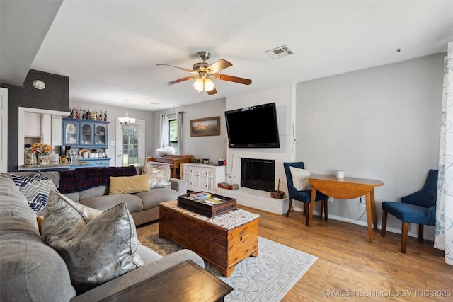 4211 E 101st St N, Sperry, OK 74073 - living area featuring ceiling fan, a chandelier, a brick fireplace, light wood-style flooring, and baseboards