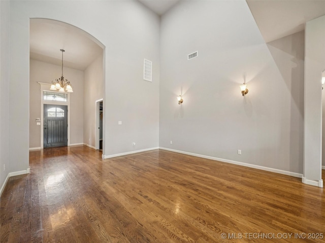 12909 S First St, Jenks, OK 74037 - unfurnished living room with arched walkways, a high ceiling, wood finished floors, baseboards, and a chandelier