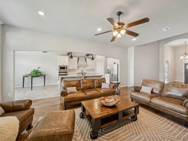 12909 S First St, Jenks, OK 74037 - living area with arched walkways, light wood-style floors, a ceiling fan, recessed lighting, and baseboards