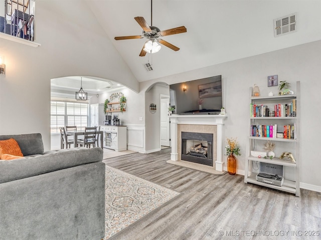 12411 E 90th St N, Owasso, OK 74055 - living area with arched walkways, wood finished floors, ceiling fan, high vaulted ceiling, and a tiled fireplace