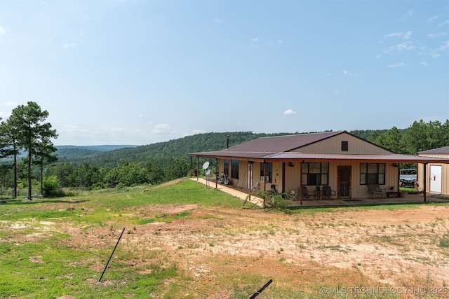 3819 129th Rd, Panola, OK 74559 - rear view of property with metal roof, a view of trees, a patio area, and board and batten siding