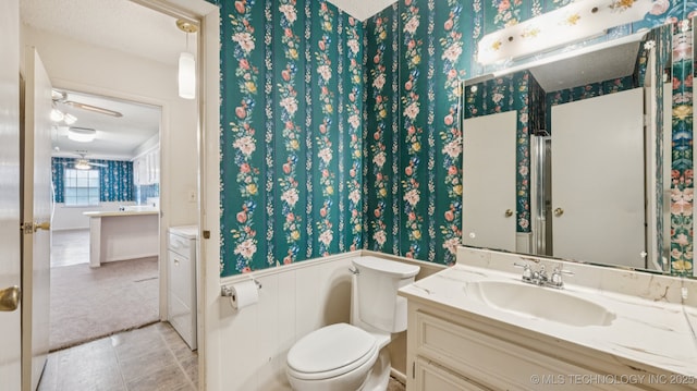 22112 W Coyote Trl Unit S, Sand Springs, OK 74063 - bathroom with vanity, toilet, a wainscoted wall, wallpapered walls, and ceiling fan