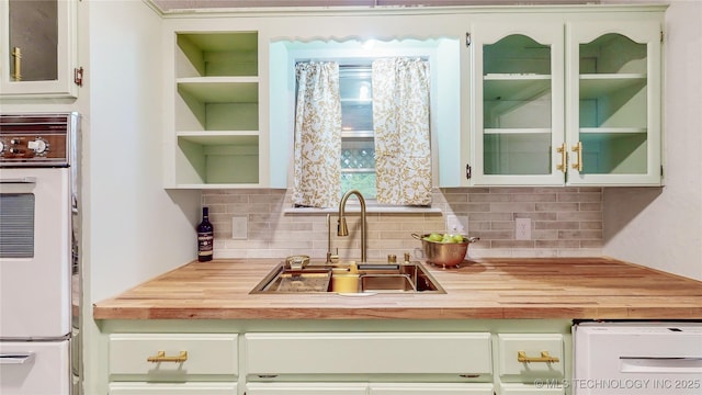 1120 N Juniper Pl, Broken Arrow, OK 74012 - kitchen with a sink, butcher block counters, decorative backsplash, glass insert cabinets, and white cabinets