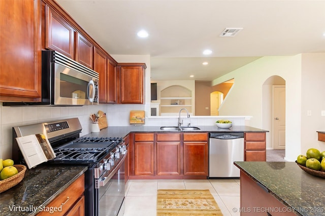 324 E 125th Pl S, Jenks, OK 74037 - kitchen featuring stainless steel appliances, a sink, arched walkways, dark stone countertops, and recessed lighting