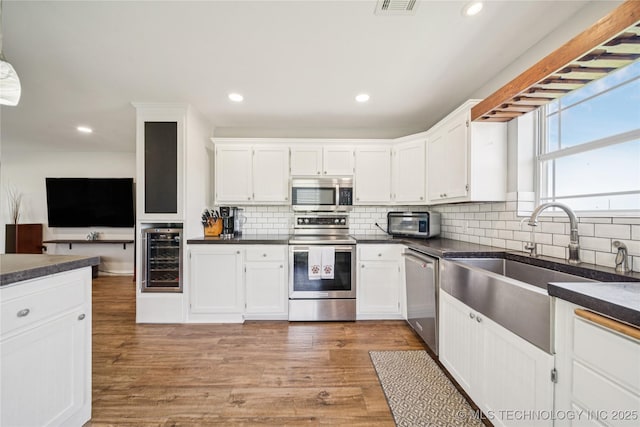 31102 S 4190th Rd, Inola, OK 74036 - kitchen featuring appliances with stainless steel finishes, beverage cooler, dark countertops, white cabinets, and tasteful backsplash
