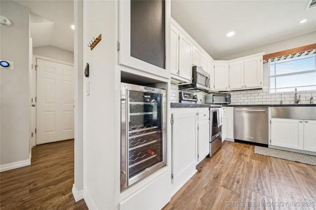 31102 S 4190th Rd, Inola, OK 74036 - kitchen with appliances with stainless steel finishes, wine cooler, dark countertops, backsplash, and white cabinets