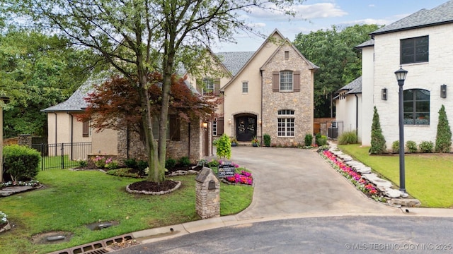 5912 E 119th St, Tulsa, OK 74137 - french country inspired facade with stone siding, central air condition unit, and concrete driveway