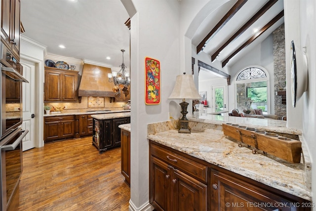 5912 E 119th St, Tulsa, OK 74137 - kitchen with wood finished floors, custom range hood, backsplash, arched walkways, and recessed lighting