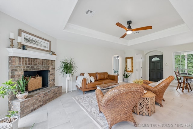 11587 W 86th St S, Sapulpa, OK 74066 - living room featuring a raised ceiling, ceiling fan, a fireplace, light tile patterned floors, and arched walkways