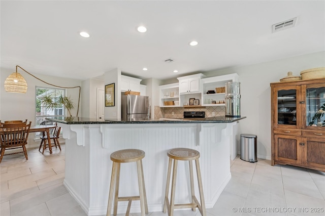 11587 W 86th St S, Sapulpa, OK 74066 - kitchen with open shelves, freestanding refrigerator, decorative backsplash, white cabinetry, and a kitchen breakfast bar