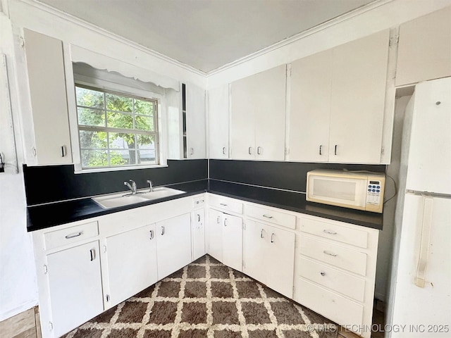 226 W Seneca St, Tahlequah, OK 74464 - kitchen featuring white appliances, a sink, dark countertops, white cabinetry, and crown molding