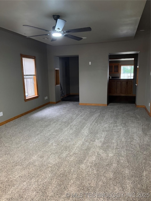 910 E Maple St, Cushing, OK 74023 - unfurnished living room with baseboards, a ceiling fan, and carpet flooring
