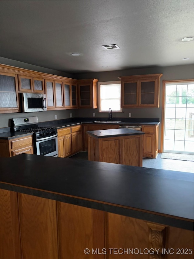 910 E Maple St, Cushing, OK 74023 - kitchen featuring appliances with stainless steel finishes, a center island, dark countertops, and plenty of natural light