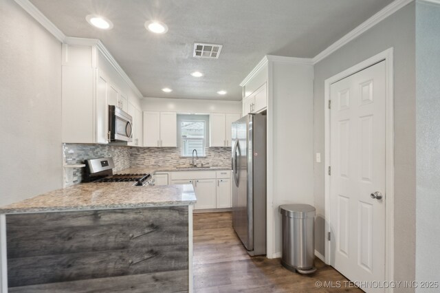 4126 E 36th Pl, Tulsa, OK 74135 - kitchen featuring appliances with stainless steel finishes, a sink, backsplash, dark wood-type flooring, and white cabinets