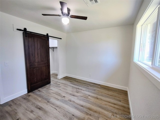 1400 NE 3rd St, Pryor, OK 74361 - unfurnished bedroom with a barn door, wood finished floors, baseboards, and ceiling fan