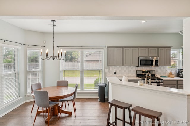 19804 E 45th St S, Broken Arrow, OK 74014 - kitchen featuring appliances with stainless steel finishes, gray cabinets, dark wood-style floors, a breakfast bar area, and decorative backsplash