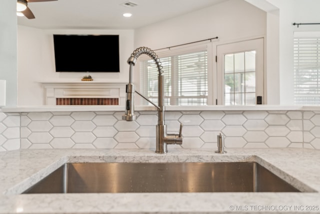 19804 E 45th St S, Broken Arrow, OK 74014 - detailed view of decorative backsplash, a sink, light stone counters, a ceiling fan, and recessed lighting