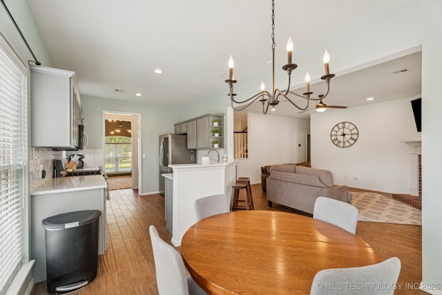 19804 E 45th St S, Broken Arrow, OK 74014 - dining area featuring wood finished floors, a chandelier, recessed lighting, baseboards, and a fireplace