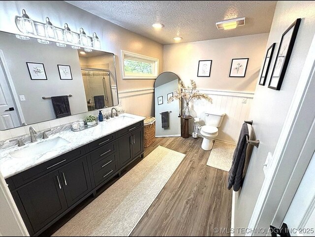 3109 Buffalo Ln, Grove, OK 74344 - full bath featuring a textured ceiling, toilet, a shower stall, double vanity, and wood finished floors