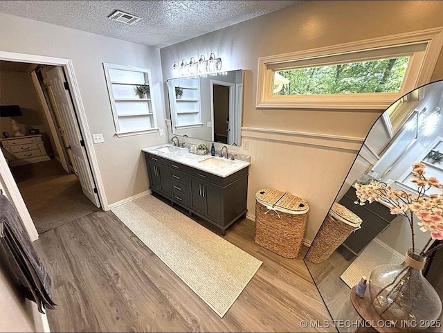 3109 Buffalo Ln, Grove, OK 74344 - bathroom with wood finished floors, double vanity, a textured ceiling, and a wainscoted wall