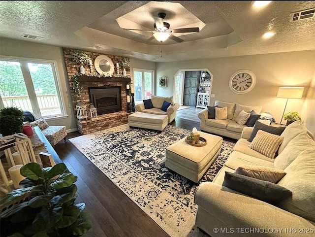 3109 Buffalo Ln, Grove, OK 74344 - living area with a textured ceiling, a ceiling fan, dark wood-style flooring, a tray ceiling, and arched walkways