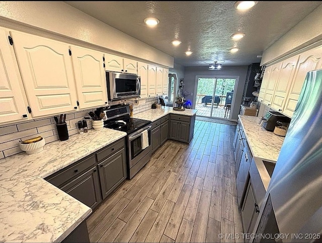 3109 Buffalo Ln, Grove, OK 74344 - kitchen with stainless steel appliances, wood finished floors, backsplash, a peninsula, and recessed lighting