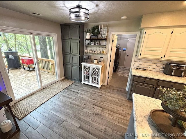 3109 Buffalo Ln, Grove, OK 74344 - kitchen with a textured ceiling, wood finished floors, tasteful backsplash, light stone counters, and baseboards