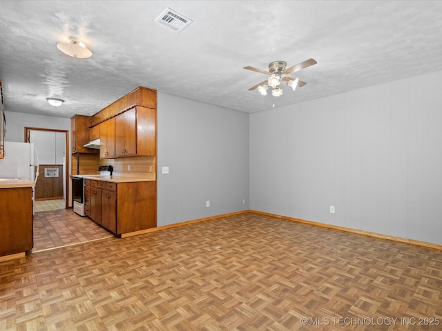 1921 S Santa Fe Pl, Bartlesville, OK 74003 - kitchen featuring white appliances, light countertops, a ceiling fan, brown cabinetry, and under cabinet range hood
