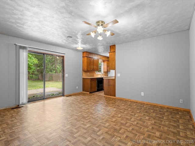 1921 S Santa Fe Pl, Bartlesville, OK 74003 - kitchen with brown cabinetry, plenty of natural light, light countertops, ceiling fan, and wooden walls