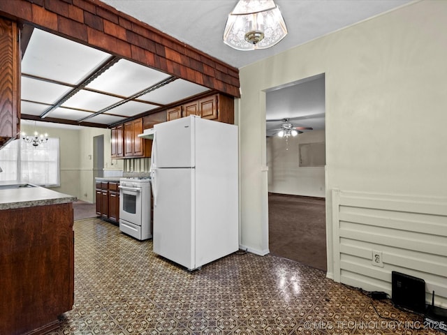 512 W 20th, Bartlesville, OK 74003 - kitchen with white appliances, a sink, a ceiling fan, a chandelier, and dark countertops