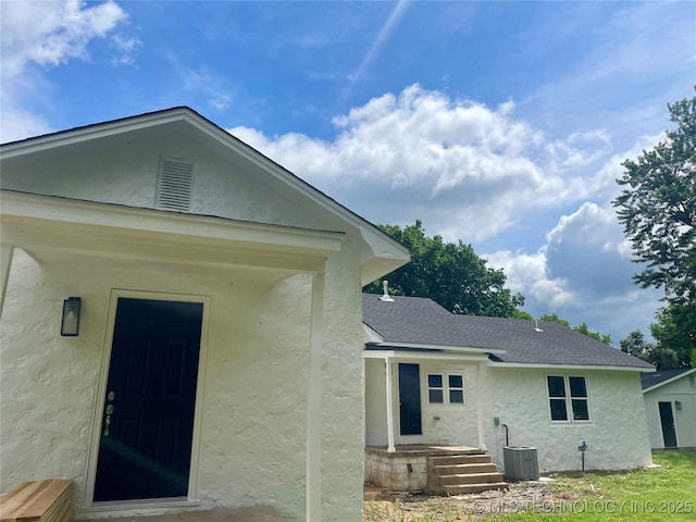 305 E Hickory Ave, Fort Gibson, OK 74434 - back of house featuring stucco siding, central air condition unit, and roof with shingles
