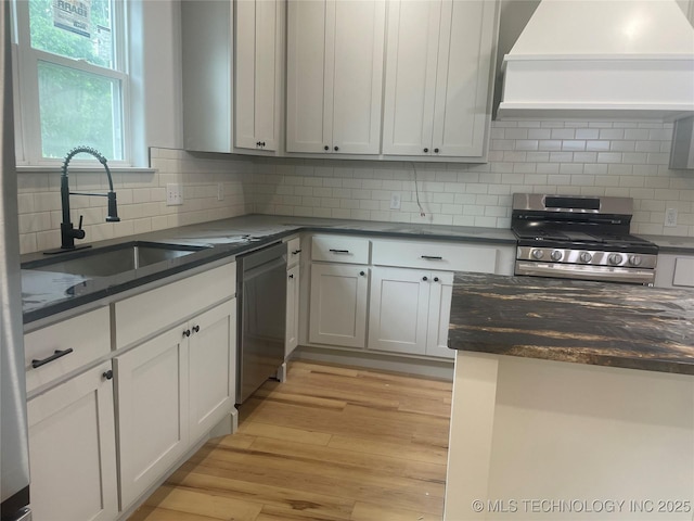 305 E Hickory Ave, Fort Gibson, OK 74434 - kitchen with appliances with stainless steel finishes, premium range hood, a sink, tasteful backsplash, and light wood-type flooring