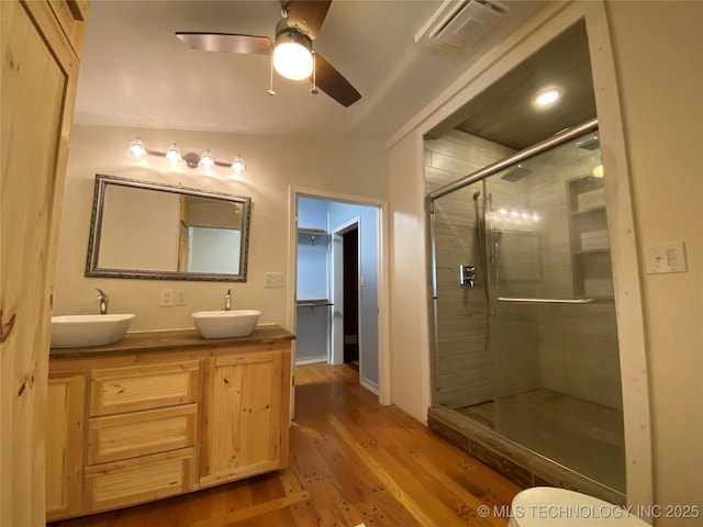 1501 E Okmulgee St, Muskogee, OK 74403 - bathroom featuring a stall shower, double vanity, wood finished floors, a ceiling fan, and baseboards