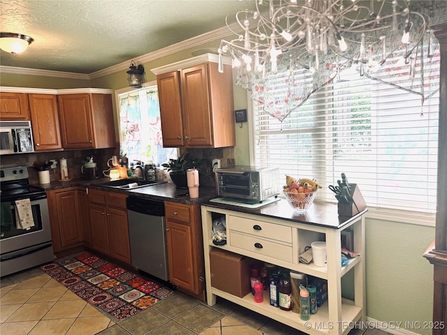 14009 S 295th E Ave, Coweta, OK 74429 - kitchen featuring stainless steel appliances, a chandelier, dark countertops, light tile patterned flooring, and ornamental molding